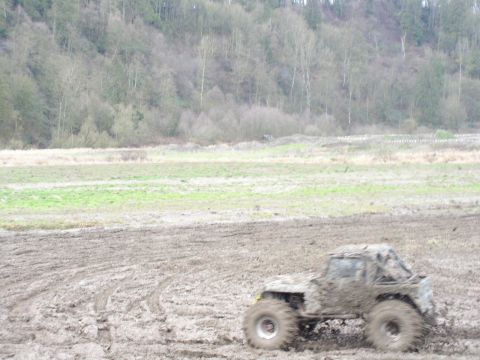 Mud-covered off-road vehicle with roll cage in a muddy field