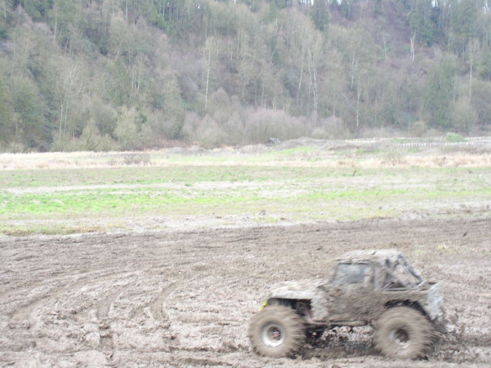 Mud-covered off-road vehicle with roll cage in a muddy field