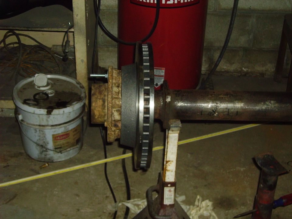 Axle assembly with a new brake rotor mounted, supported by jack stands in a workshop