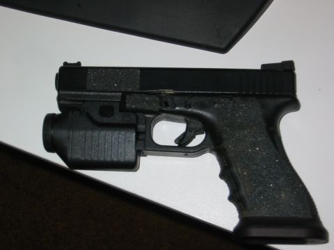 1996 Ford Bronco - A black pistol with a mounted flashlight is shown from the side against a white background.