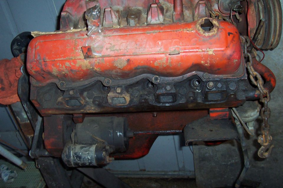Orange engine block with black intake manifold and valve covers, some rust visible