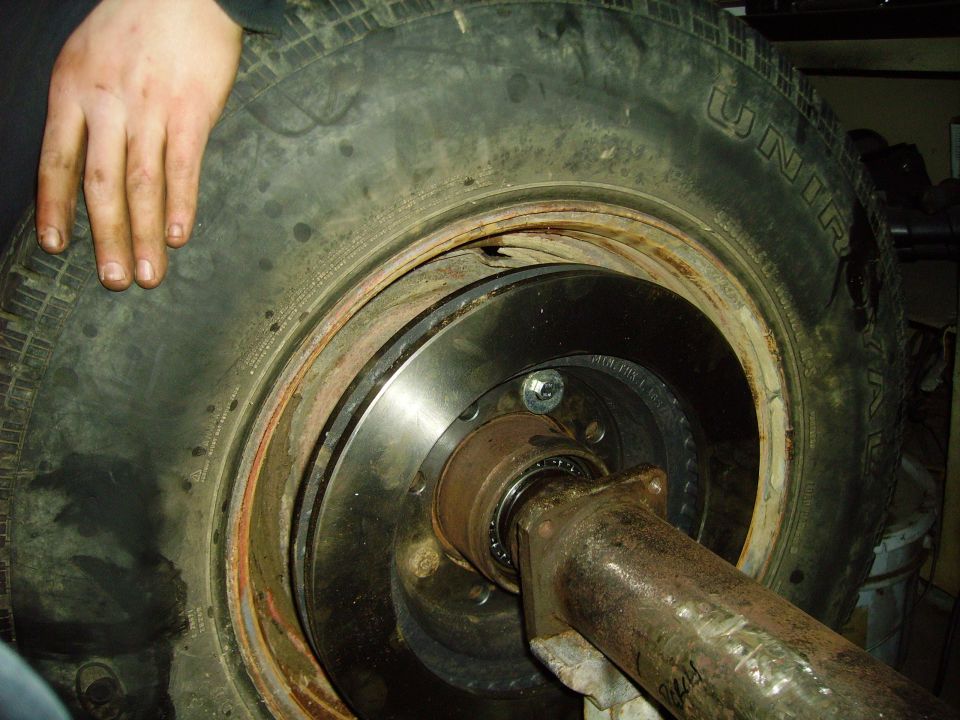 Wheel hub assembly with brake rotor and tire. A hand rests on the tire