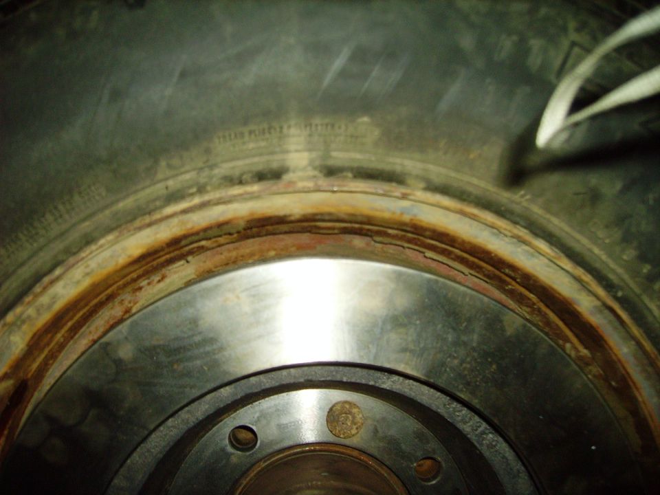 Close-up of a worn brake rotor face with rusty edge behind a tire