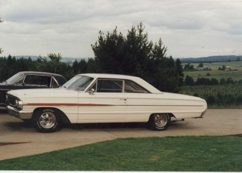 1971 Ford Mustang - A white 1963 Ford Galaxie 500 is parked next to another vehicle with a scenic rural background.