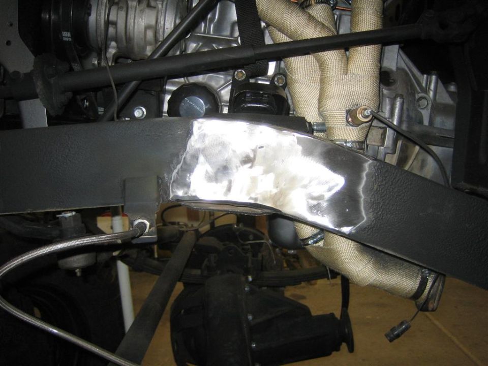 close-up of a welded section on a vehicle frame, with engine components and exhaust pipes visible
