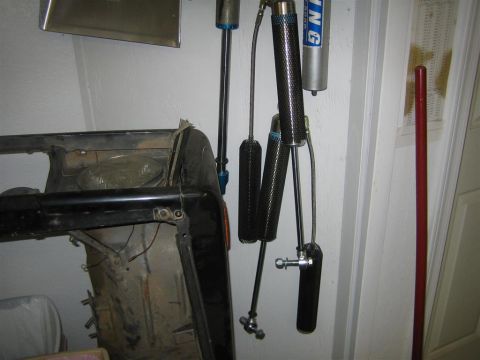 1987 Suzuki Samurai - Suspension shocks and a section of a vehicle frame are displayed on a wall.