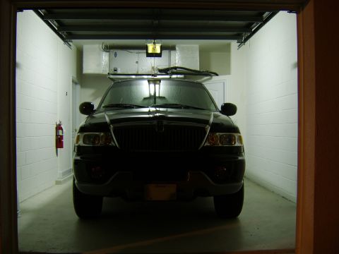 1996 Mercury Grand Marquis - A black SUV is parked head-on inside a garage, with the garage door partially open.