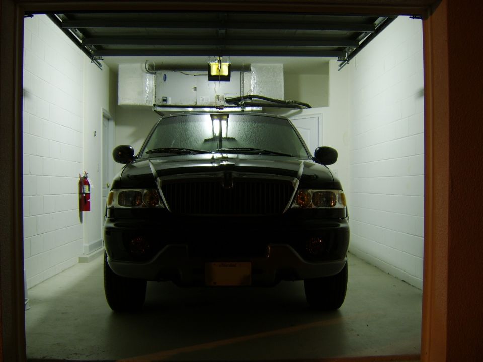 Black Lincoln SUV parked front-on in a white garage with lights on