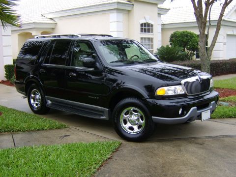 1996 Mercury Grand Marquis - A black SUV is parked on a concrete driveway in front of a house.