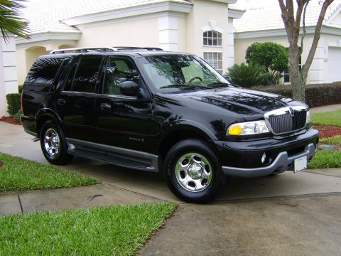1996 Mercury Grand Marquis - A black Lincoln Navigator SUV is parked on a concrete driveway with a house in the background.
