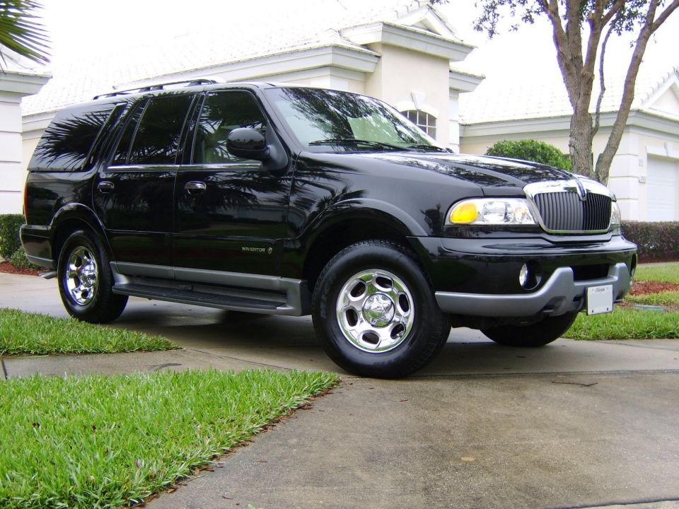Black Lincoln Navigator SUV, chrome grille and wheels, parked in a driveway