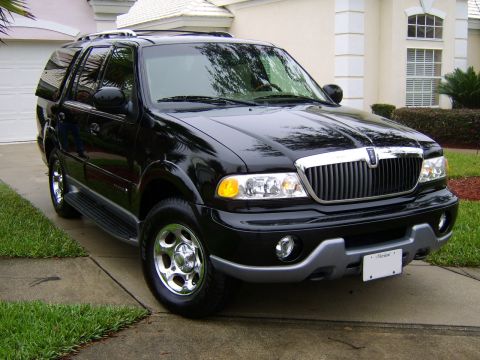 1996 Mercury Grand Marquis - A black Lincoln Navigator SUV is parked in front of a house on a paved driveway.