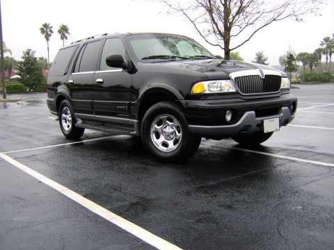 1996 Mercury Grand Marquis - Black Lincoln Navigator SUV parked in a wet lot on an overcast day.