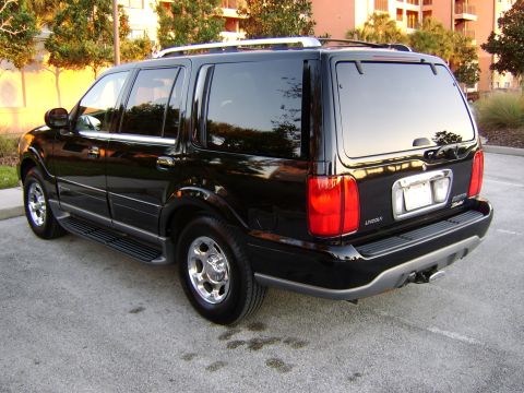 1996 Mercury Grand Marquis - This black Lincoln Navigator is parked in a lot with trees and buildings in the background.