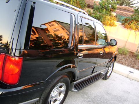 1996 Mercury Grand Marquis - Side view of a black SUV with tinted windows reflecting a building.
