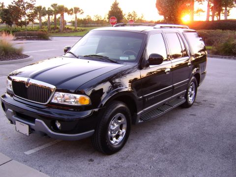 1996 Mercury Grand Marquis - A black Lincoln Navigator is parked in a lot with palm trees and a sunset in the background.