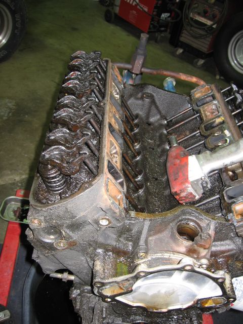 1990 Ford Bronco - Close-up view of an engine block's internal components, including valves and springs, heavily coated in oil.