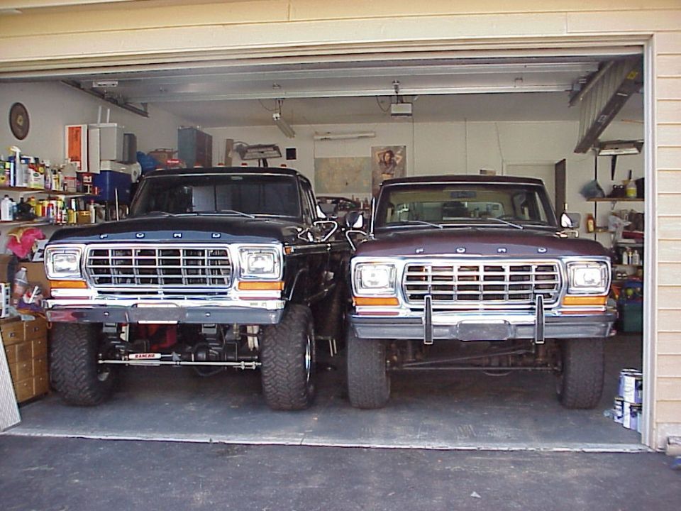 Two 1979 Ford Broncos parked nose-to-nose in a garage