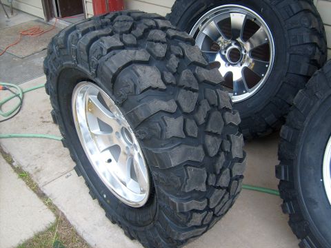 1989 Ford Bronco - Close-up of aggressive off-road tires and shiny rims, likely for a truck or SUV.