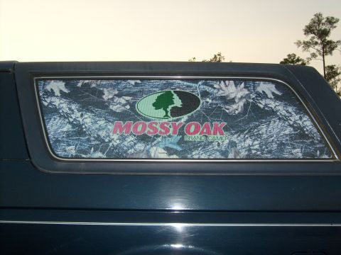 1989 Ford Bronco - The rear window of a vehicle features a Mossy Oak Brand Camo decal over a camouflage pattern.
