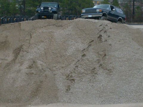 1989 Ford Bronco - A 1989 Ford Bronco and a Jeep are positioned on a large pile of gravel.