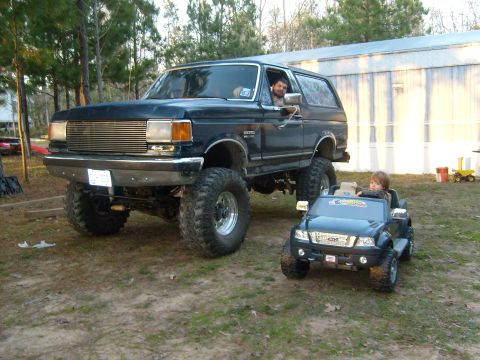 1989 Ford Bronco - A lifted 1989 Ford Bronco is parked next to a child's toy Ford Ranger.