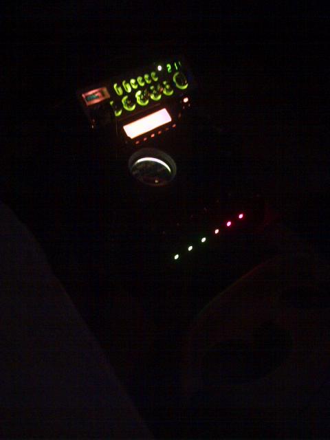 1994 Ford Bronco - Interior view of illuminated dashboard switches and a gauge, with some lights showing red and green.