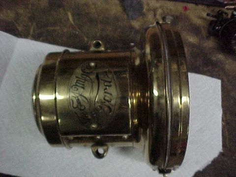 1912 Ford Model T - A brass Ford lamp, likely a headlight, is shown up close with embossed lettering.