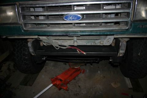 1991 Ford Bronco - Front view of a 1991 Ford Bronco, showing the grille, bumper, and tires, with a jack positioned below.