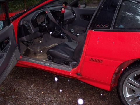 1991 Mitsubishi Eclipse - Interior view of a red 1991 Mitsubishi Eclipse, driver's side door open, revealing the cabin and an AWD badge.
