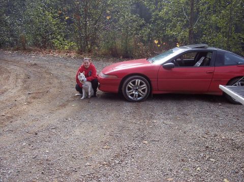 1991 Mitsubishi Eclipse - A red 1991 Mitsubishi Eclipse coupe is parked on a gravel surface with a person and a dog posing beside it.