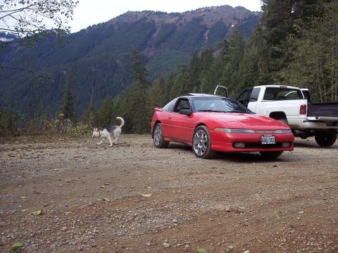 1991 Mitsubishi Eclipse - Red 1991 Mitsubishi Eclipse and white pickup truck in a mountainous, wooded area.