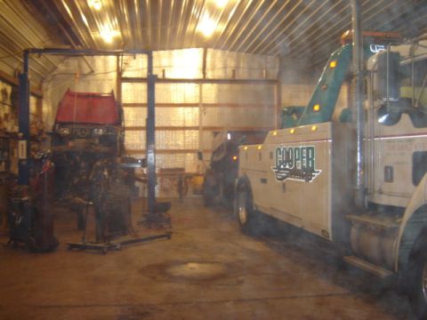 1992 Ford Bronco - A tow truck is parked inside a garage next to another vehicle on a lift.