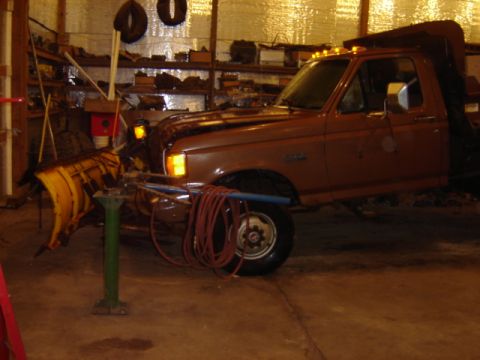 1992 Ford Bronco - This dump truck is equipped with a snow plow and appears to be stored indoors.