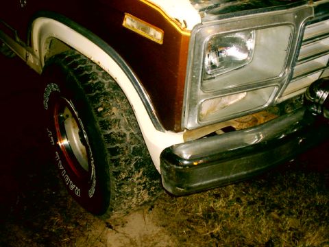 Front fender and tire of a 1980 Ford Bronco. Chrome bumper and grille visible
