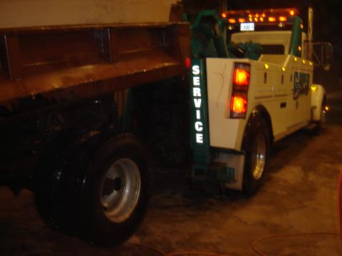1992 Ford Bronco - A tow truck is shown from behind, with its dump bed raised slightly.