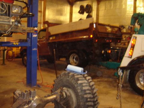 1992 Ford Bronco - A dump truck is parked inside a garage, with another vehicle partially visible on the right.