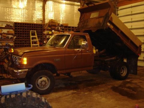 1992 Ford Bronco - A brown dump truck is parked inside a garage, with its bed raised. The truck appears to be a 1992 Ford F-series model.