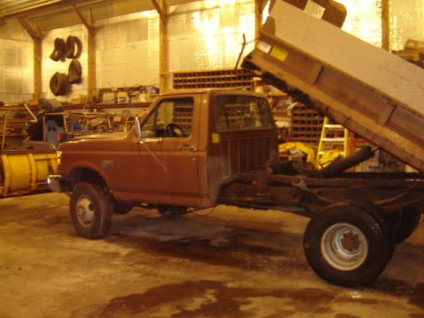 1992 Ford Bronco - Side view of a dump truck chassis and cab, with the dump bed in the raised position.