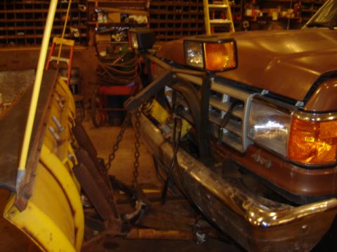 1992 Ford Bronco - Front view of a brown Ford truck equipped with a snow plow, showing its grille and bumper.