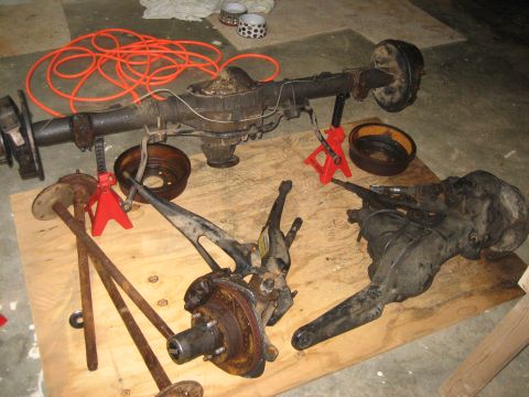 1996 Ford Bronco - Various automotive axle and suspension components are displayed on a wooden platform, suggesting a repair or restoration project.