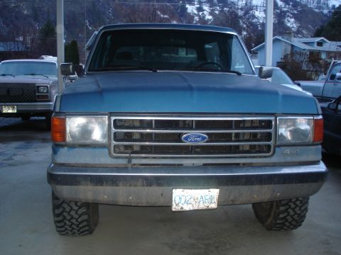 1990 Ford Bronco - This blue Ford F-Series truck has a prominent grille and 4x4 badging, indicating its model year.