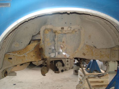 1990 Ford Bronco - The underside of a vehicle shows significant rust and wear around the wheel well and suspension parts.