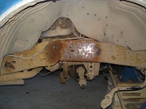 1990 Ford Bronco - Underside view of heavily rusted vehicle frame and suspension components, with some parts removed.