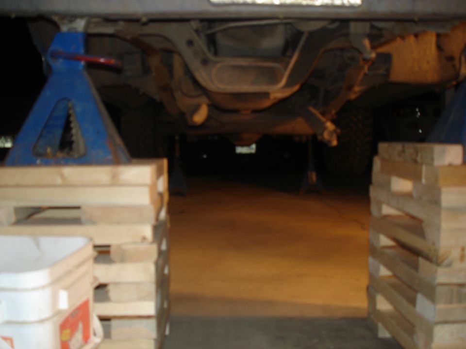 Undercarriage of vehicle on jack stands, showing suspension and exhaust components