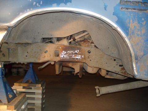 1990 Ford Bronco - Close-up of the rear suspension and frame of a 1990 Ford Bronco, elevated on jack stands.