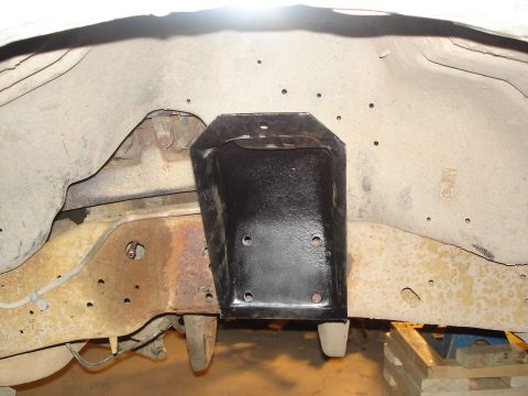 1990 Ford Bronco - Close-up of a black frame bracket attached to a rusty vehicle chassis.