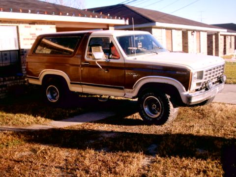 Brown and white Ford Bronco parked in front of a house