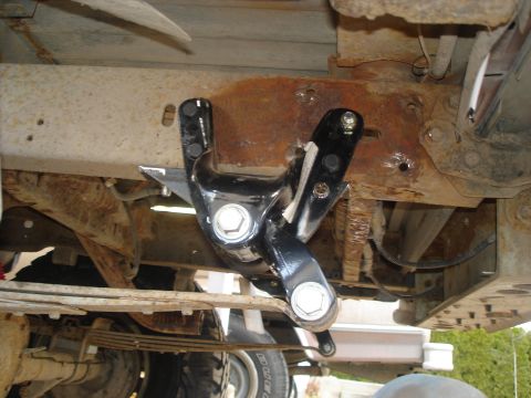 1990 Ford Bronco - Close-up view of a vehicle's undercarriage showing a new bracket attached to a rusty frame.