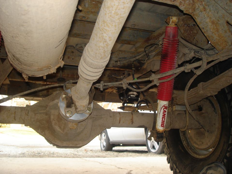Undercarriage view showing differential, driveshaft, and Rancho shock absorber. Another vehicle is visible in the background